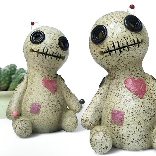 Two cute voodoo doll incense holders with beige speckled bodies, pink hearts, and black button eyes, shown on a white background with a small green plant prop |DIVINE TIMES by Shopp Java